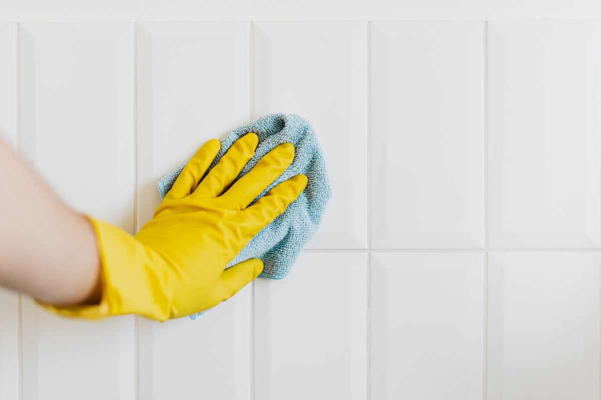 Person cleaning wall tiles with cloth