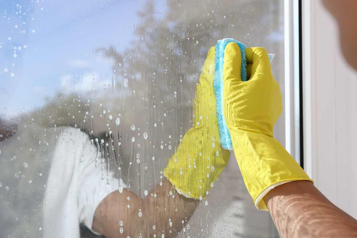 Man cleaning window glass with cloth indoors