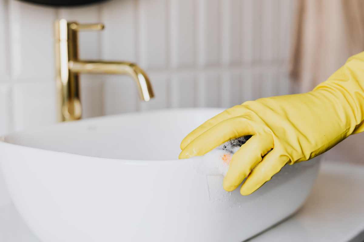 Person in glove cleaning breakroom sink