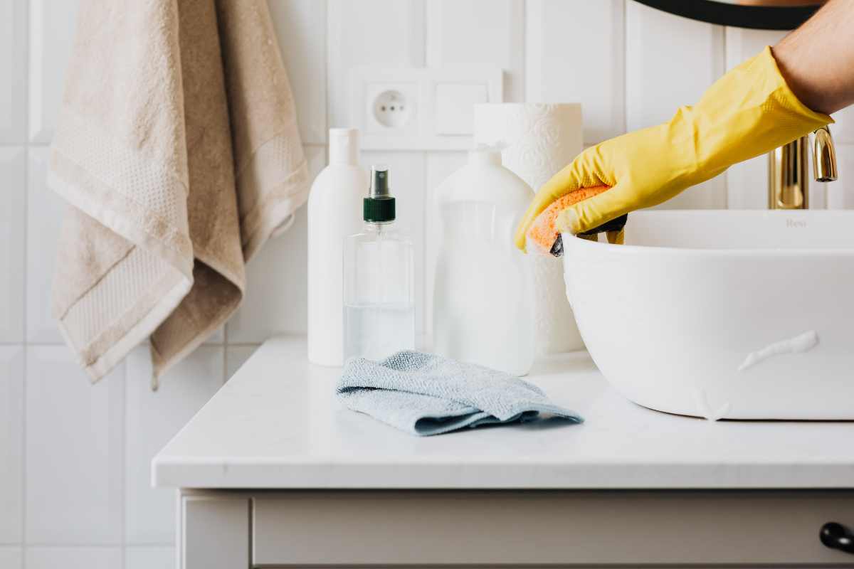 Person disinfecting sink surface in modern restroom