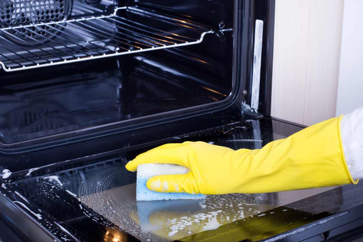 Woman cleaning oven appliance in kitchen