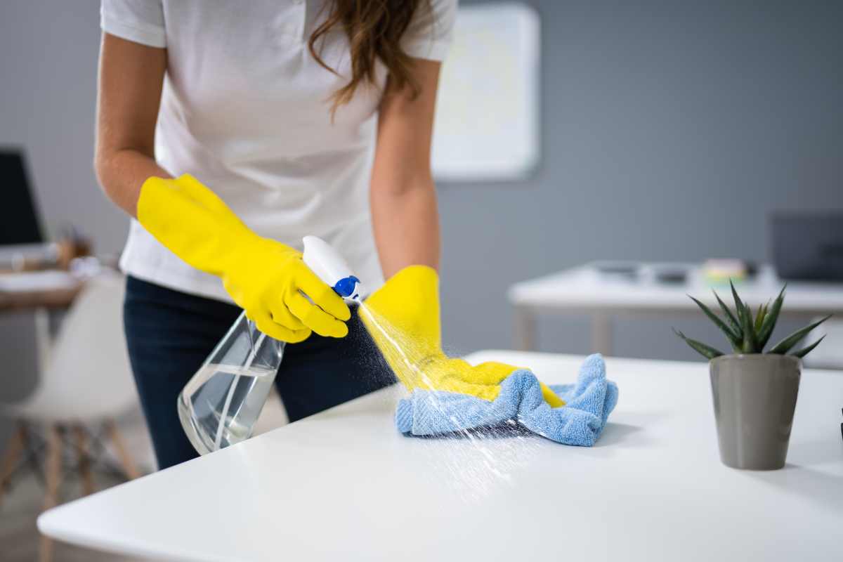 Worker cleaning shared breakroom surface with cloth